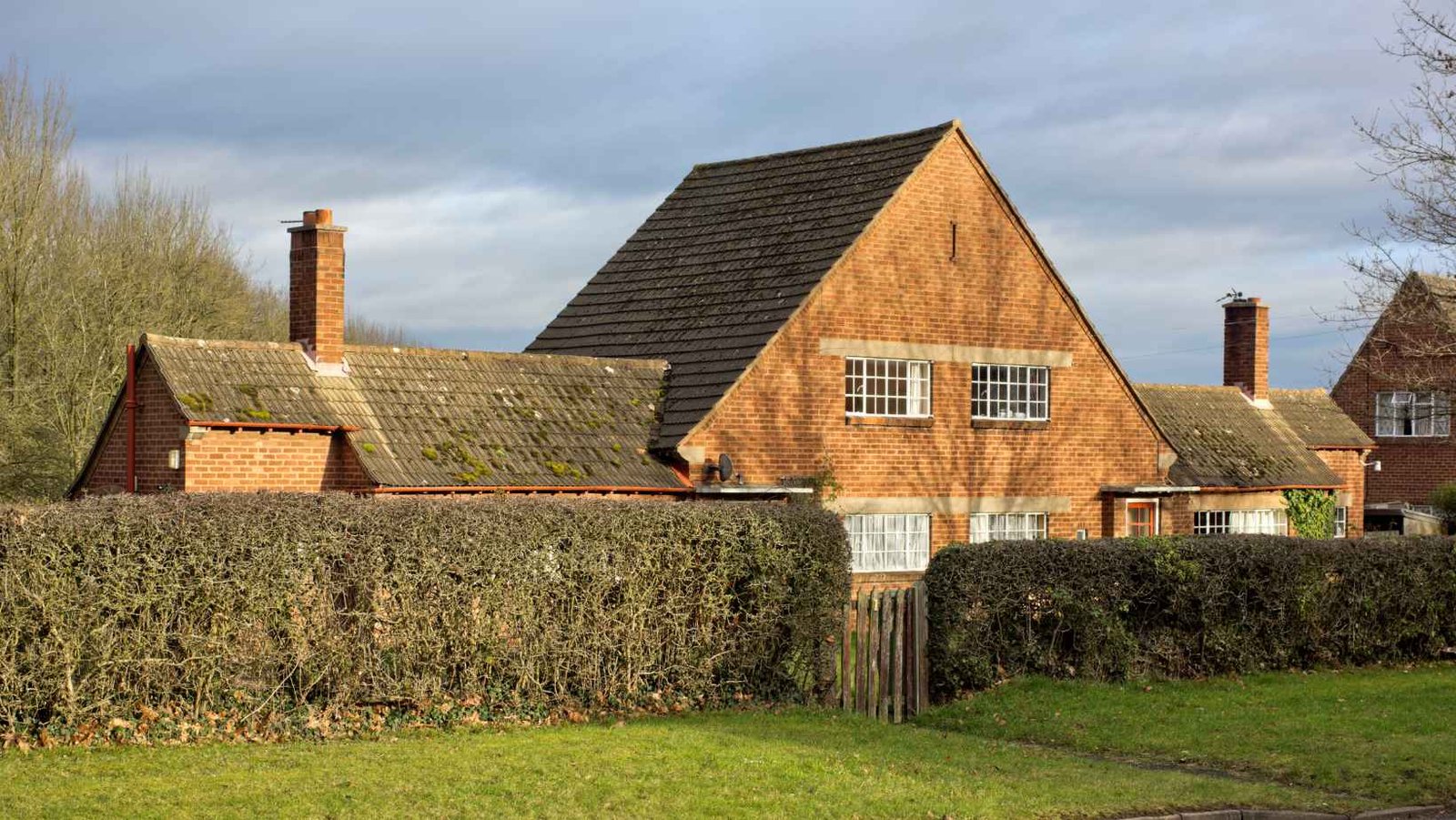Farmhouse with a stone chimney behind a hedge