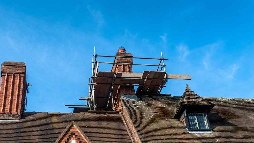 Brick chimney rebuild with scaffolding on the roof